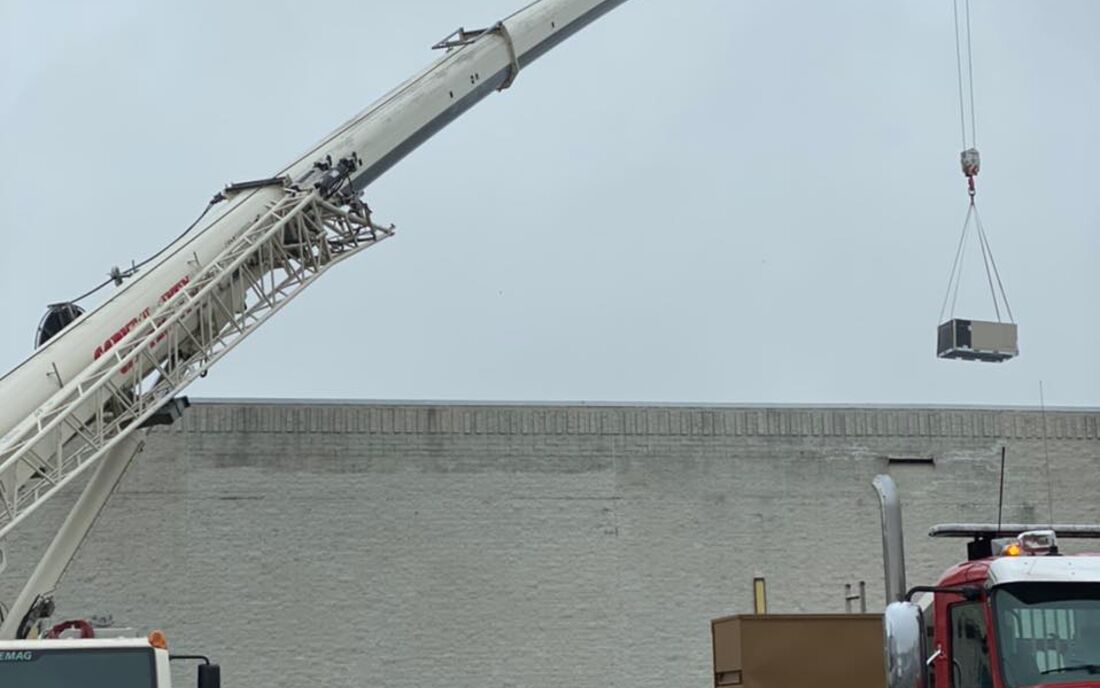 Crane lifting a rooftop HVAC unit into place
